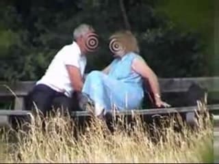 A mature couple have some fun on a bench